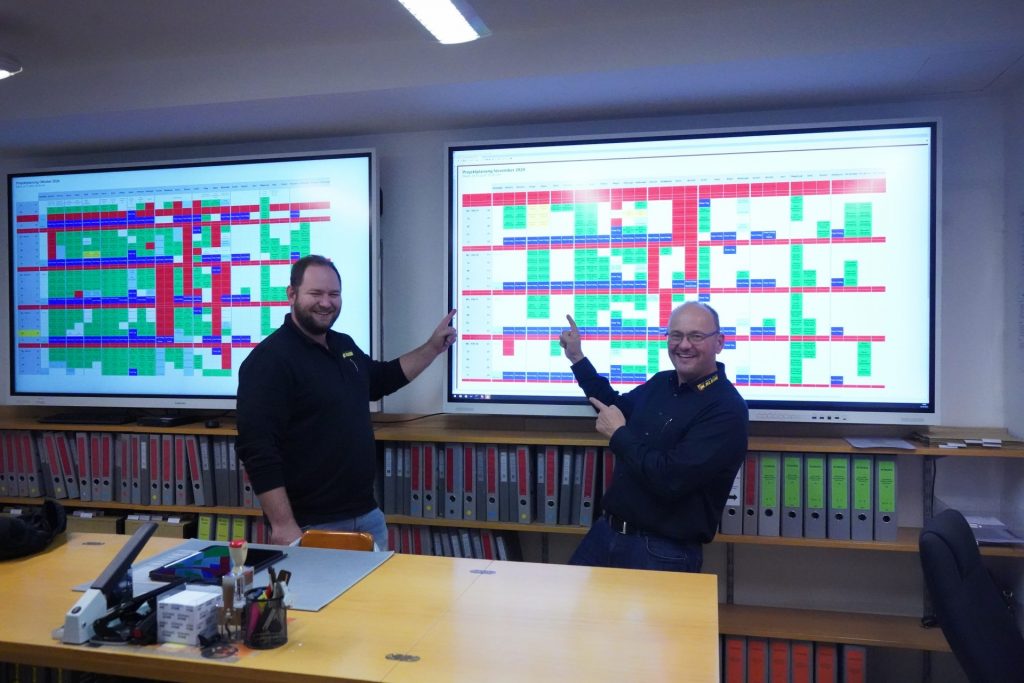 Jonas Brandt und Wolfgang Klein mit der Plantafel von KWP im Hintergrund